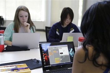 Students studying drag and drop coding on a computer